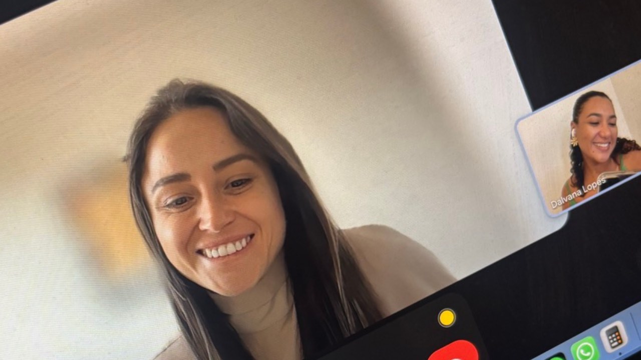 Aluna sorrindo em aula do Conversation Club, com a professora no canto da tela